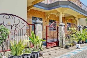 GresikOYO 93108 Homestay H Syarif Syariah – RA Kartini的红门,在有盆栽植物的房子前