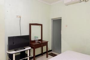 Global Inn Syariah Mitra RedDoorz near Juanda T1 Airport的一间卧室配有电视、镜子和一张床