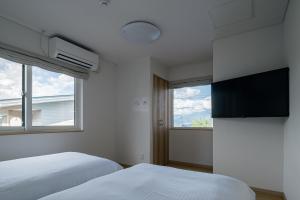 富良野Casi 15的一间卧室设有两张床、一台电视和一扇窗户。