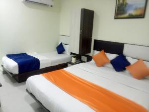 艾哈迈达巴德hotel royal night的一间卧室配有两张带橙色和蓝色枕头的床