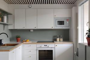 海门林纳Kodikas juuri remontoitu yksiö keskustassa的厨房配有白色橱柜和炉灶烤箱。