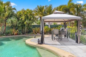 UranganPrivate Resort-style Queenslander at Hervey Bay的一个带桌子的庭院和一个毗邻游泳池的凉亭