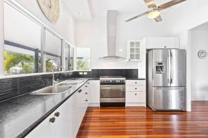 UranganPrivate Resort-style Queenslander at Hervey Bay的厨房配有白色橱柜和不锈钢冰箱