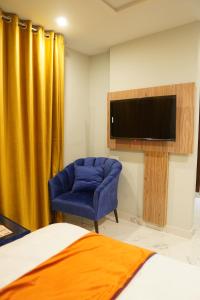 伊斯兰堡Nüva Hotel的一间卧室配有蓝色椅子和一台平面电视