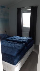 卡兰茨奥赫CS 34 - Vakantiepark Callassande的一间卧室配有一张带蓝色床单的床和一扇窗户。