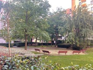 马恩河畔尚Les Aubépines entre Disney et Paris的公园里三个长椅,有树木和建筑物