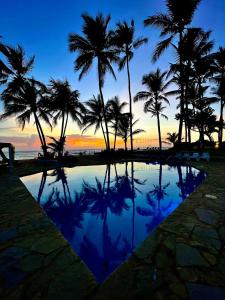 喀巴里特WOW location Kite Beach Oceanfront 2 Bedroom Patio and Pool的日落时分棕榈树和海洋的游泳池