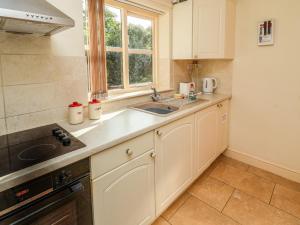 WelbournHill Top Cottage的厨房配有白色橱柜、水槽和窗户。