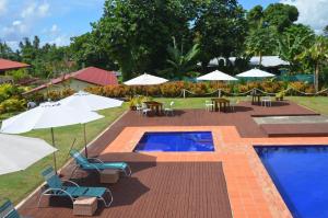 阿皮亚旅客柏银特酒店的一个带桌椅和遮阳伞的游泳池