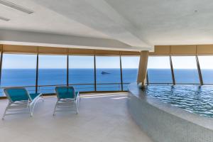 贝尼多姆Intempo planta 22 ! vistas impresionantes !的一座带椅子的建筑中的游泳池,大海