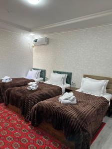 布哈拉Abuzar的两张位于酒店客房的床,配有毛巾