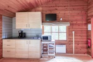KalantiPinetree Cottages Cozy log cabin的厨房配有木制橱柜、微波炉和窗户。