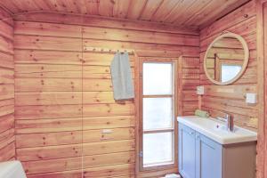 KalantiPinetree Cottages Cozy log cabin的浴室设有木墙、水槽和镜子