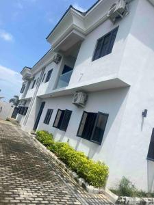 莱基Lekki holiday shortlet的鹅卵石街道上一座白色的建筑,设有黑色窗户