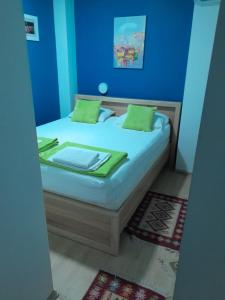 莫斯塔尔Apple Line Appartments的蓝色卧室,配有带绿色枕头的床