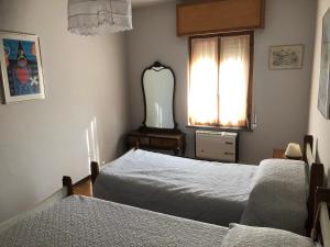 CrosaCasa Anna的一间卧室设有两张床、镜子和窗户