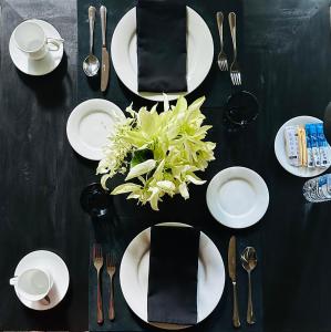希克杜沃Saffron Robes Living的一张黑桌,上面有白色的板子和餐具