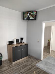 米特韦达Gästehaus Graupner-Mittweida的客房设有厨房,墙上配有电视。
