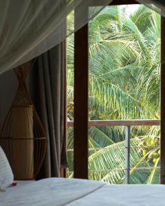 尼拉瓦利兰卡豆蔻的一间卧室设有一张床,窗户拥有棕榈树