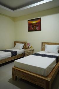 BanjarangkanUmah Desa的卧室配有两张床,墙上挂着一幅画