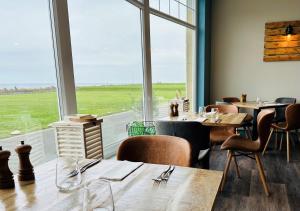 锡豪西斯Beach House Hotel的餐厅设有桌椅和大窗户。