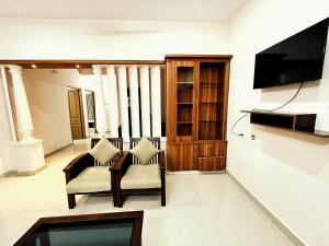 德里久尔Thrissur Villas Home Stay的客厅配有两把椅子和电视