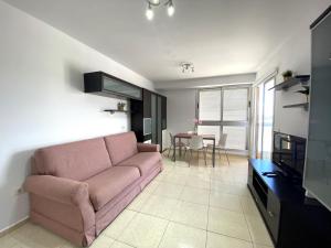 厄尔梅达诺Apartamentos Medano - La Ladera的客厅配有粉红色的沙发和桌子
