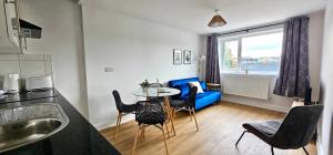 卡迪夫Harlequin Apartments by Switchback Stays的客厅配有桌子和蓝色沙发