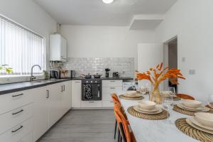 利物浦Modern 4bedroom Spacious Family Home的厨房配有白色橱柜和桌椅