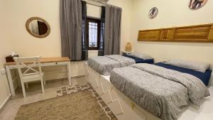 安曼Carob Hostel的一间卧室配有两张床、一张桌子和一面镜子