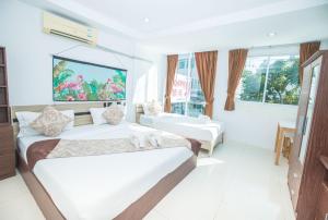 芭东海滩Happy 99 Guest house的白色的客房配有两张床和电视。