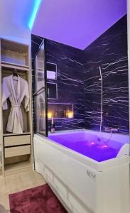 马拉科夫Relax Room proche PARIS Porte de Versailles的浴室设有黑色墙壁和紫色浴缸