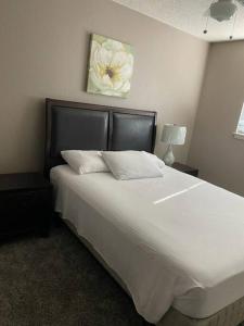 埃尔帕索Comfy Retreat的卧室配有一张白色大床,墙上挂有花卉画