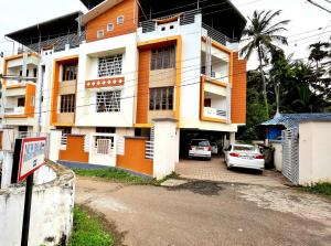 德里久尔Thrissur Villas Home Stay的前面有汽车停放的建筑