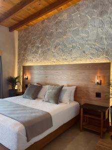 瓜达鲁佩镇MYA Hotel Boutique的一间卧室设有一张带石墙的大床