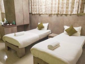 HatikhuliLe Green Kaziranga的小客房内的两张床,配有白色床单