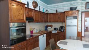 弗洛拉克FLORAC AUTHENTIQUE的厨房配有木制橱柜和白色桌子。