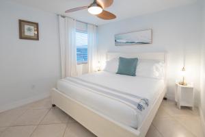 皮尔斯堡Hutchinson Island Beach House - Sleeps 32 - 8 BD的白色卧室配有床和吊扇