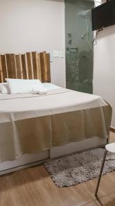 马瑙斯卡萨希尔托精品酒店的一间卧室配有一张带白色床单和地毯的床。