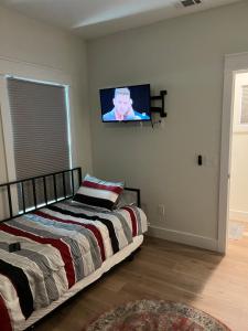 彭萨科拉The Clifford House的卧室配有一张床,墙上配有电视。