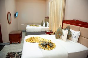 姆贝亚Royal Tughimbe Hotel的一间酒店客房,房间内设有两张床
