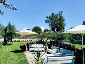 阿查拉维Olive Garden Studios & Apartments的庭院设有白色的桌子和遮阳伞,位于草地上