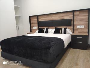 桑亨霍Apartamentos Silgar Plaza的一间卧室配有一张大床和黑色毯子