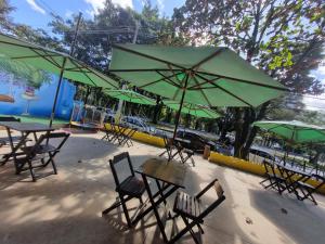坎皮纳斯Quarto Bem Star na Lagoa do Taquaral的一组桌椅,配有绿色遮阳伞