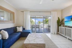 乔治敦Coconut Bay Villas #116的客厅配有蓝色的沙发和电视