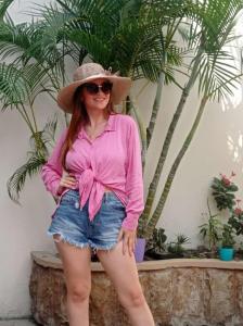 曼塔HOSTAL SAN MARINO的穿着粉色衬衫和帽子的女人