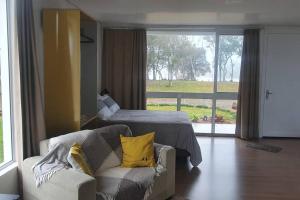 新彼得罗波利斯Alto do morro的带沙发和床的客厅以及窗户。