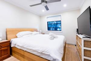 悉尼Funda Place - Leafy Hideout in Northern Beaches的一间卧室配有一张床和一台平面电视
