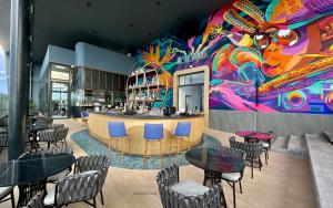 米里Mercure Miri City Centre的餐厅设有桌椅和色彩缤纷的墙壁
