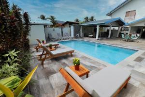 Piarco机场住宿加早餐旅馆的房屋旁的游泳池配有桌椅